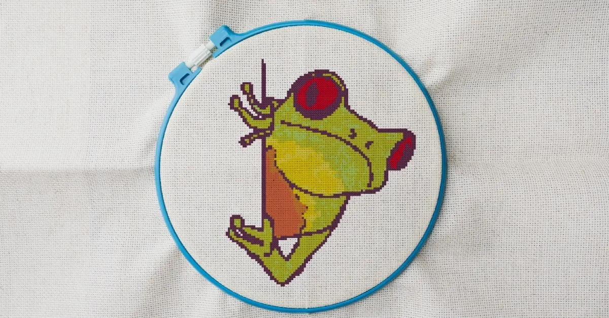 embroidered and framed in a hoop peeking tree frog cross stitch