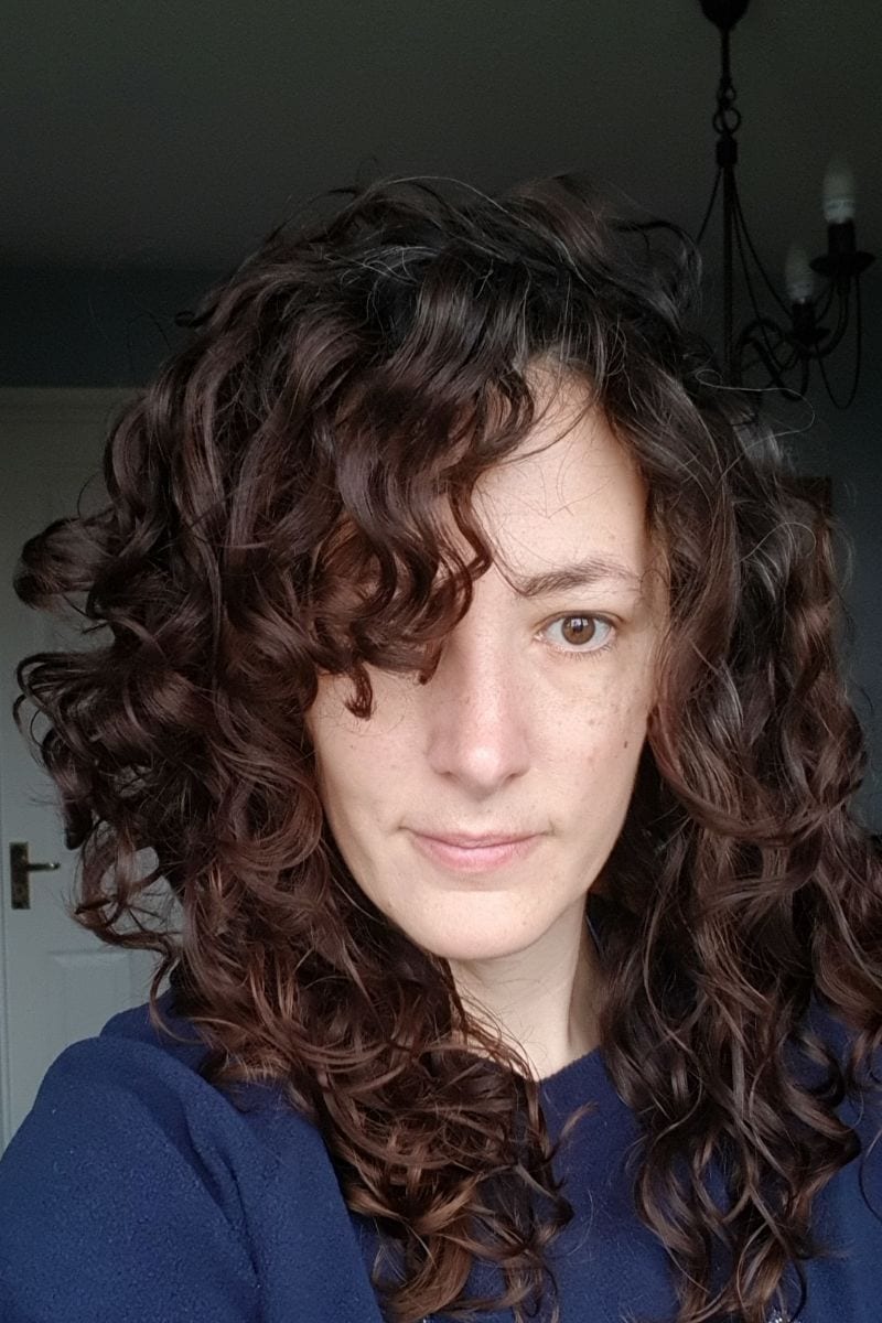 woman with dark brown curly hair looking straight at the camera