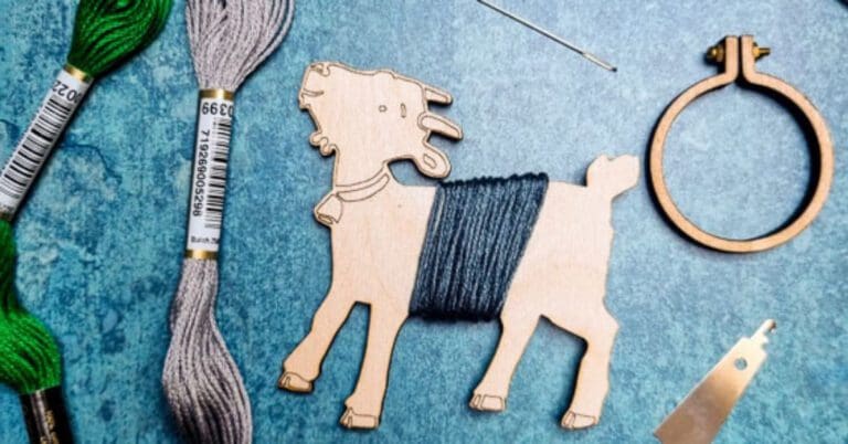 plywood Goat floss bobbin cut using a laser cutter, surrounded my other embroidery equipment on a blue background