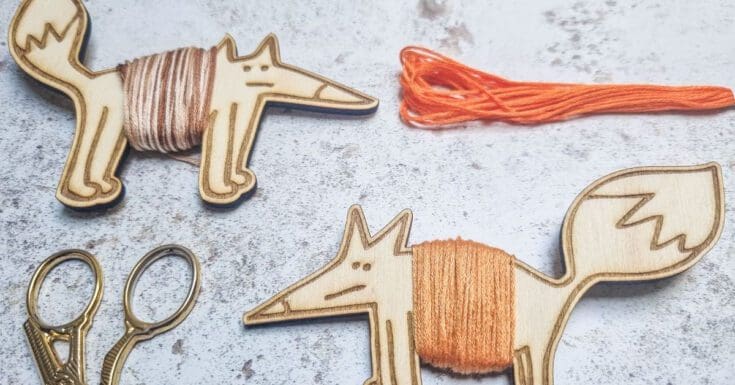 image shows two fox floss bobbins cut from a free svg file, with embroidery scissors and thread next to them