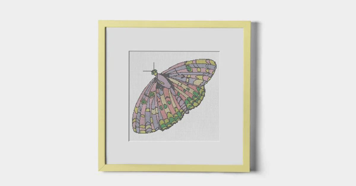 image shows embroidered spring butterfly cross stitch pattern framed in a yellow square frame against a white wall