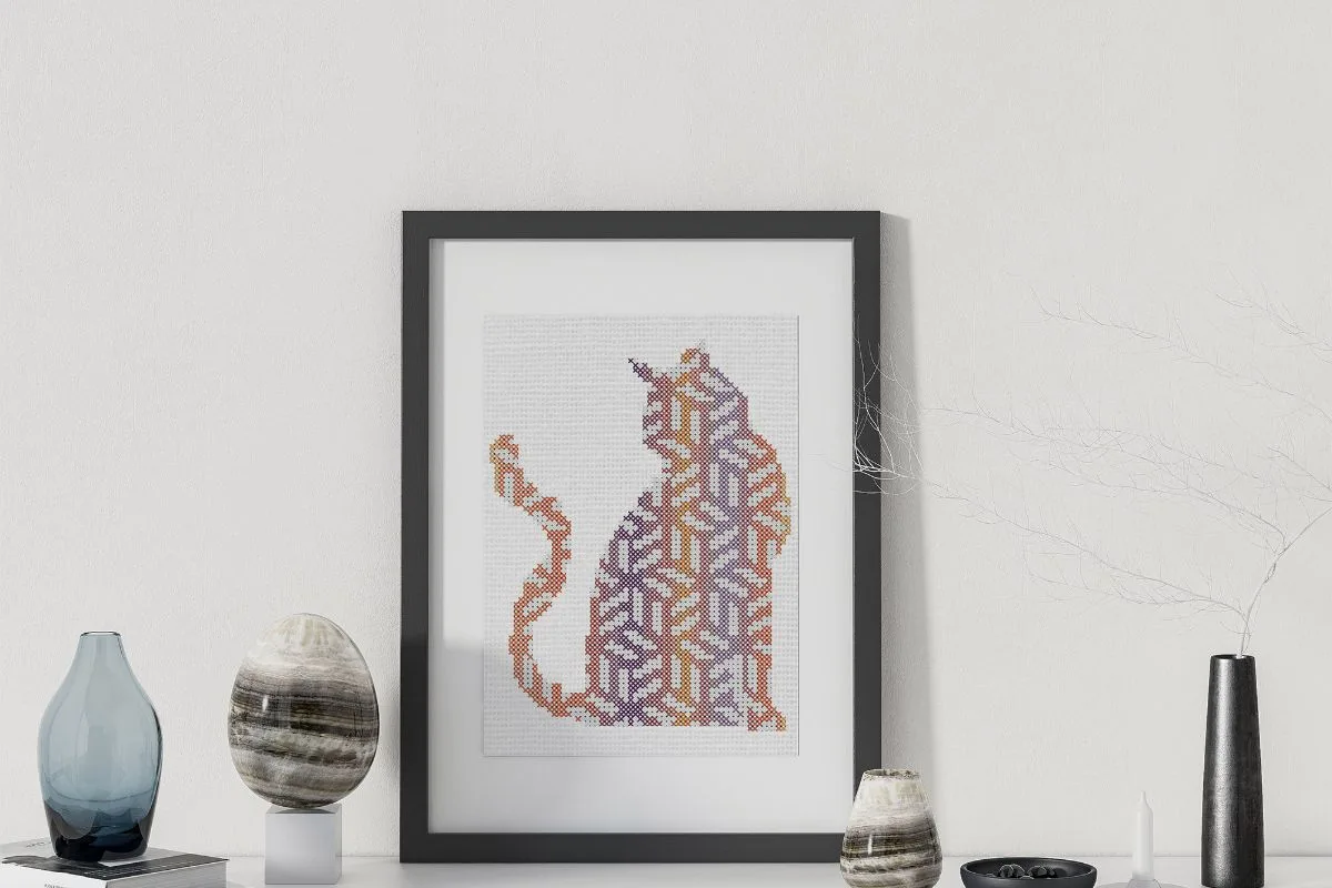 geometric cubist cat cross stitch pattern stitched and framed in a black frame
