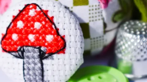 embroidered mini mushroom cross stitch made into a covered button