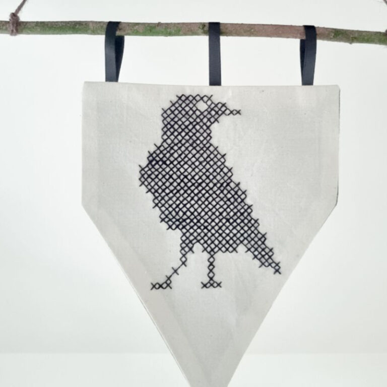 embroidered pennant made from stamped cross stitch fabric that had been laser engraved
