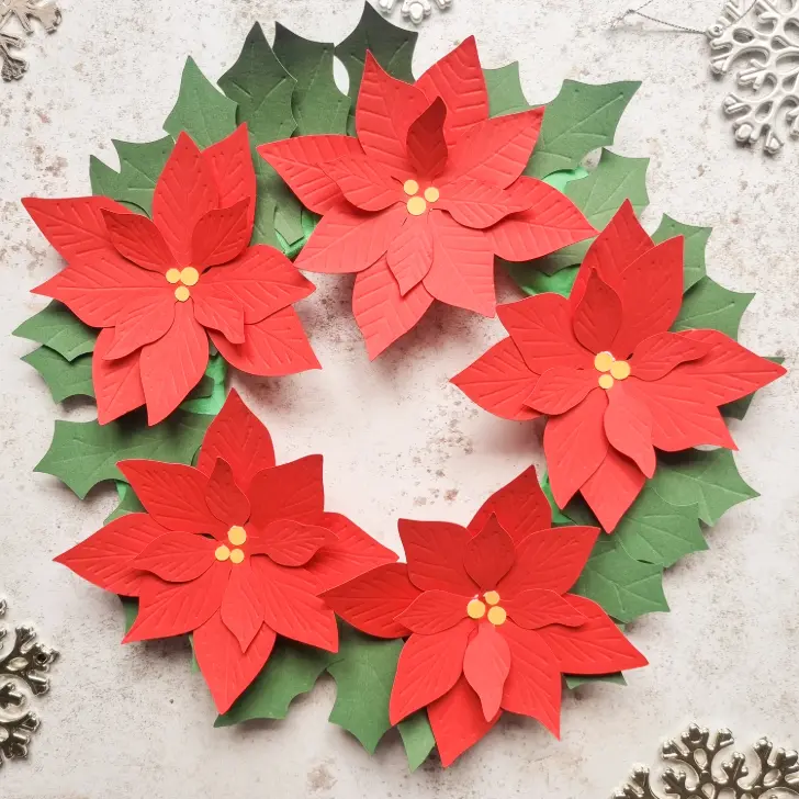 a diy made paper poinsettia and holly wreath