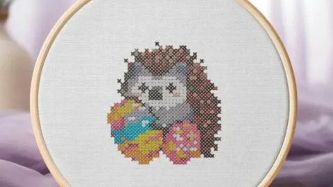 easter egg holding hedgehog cross stitch embroidered and framed in a hoop