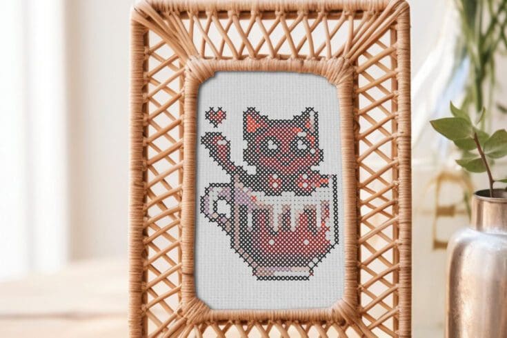 framed and embroidered cat in a cup cross stitch