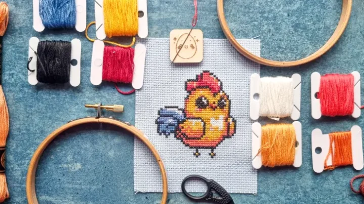 embroidered cross stitch kawaii rooster, surrounded by embroidery sewing supplies