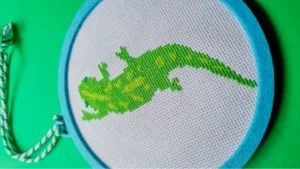 framed in a felt hoop stitched gecko cross stitch pattern on a green background