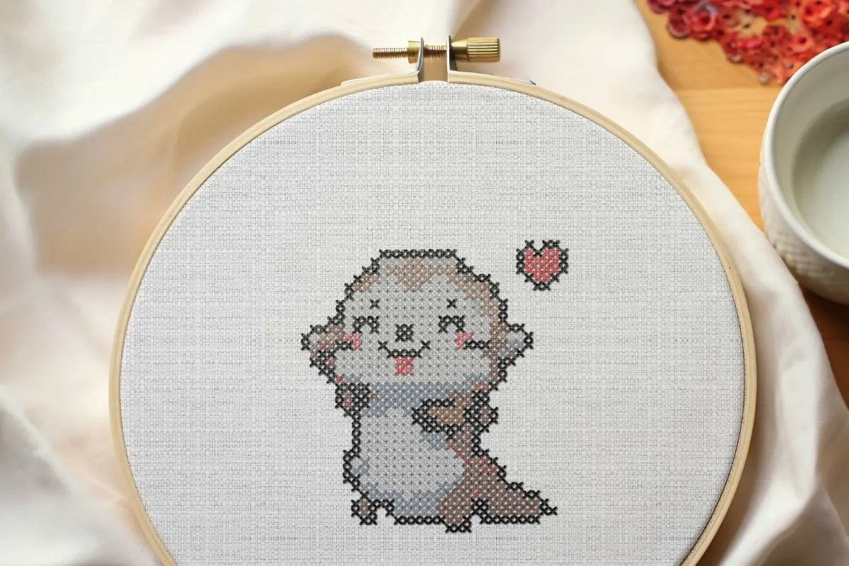 framed in a hoop and embroidered happy otter cross stitch pattern