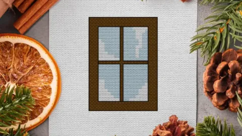 embroidered winter window cross stitch surrounded by festive foliage