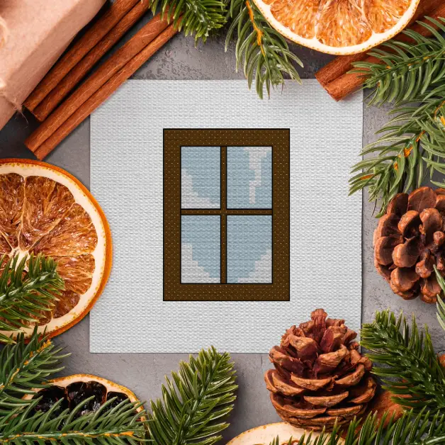 embroidered winter window cross stitch surrounded by festive foliage